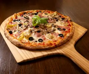 Capricciosa Pizza served with mozzarella, tomato sauce, ham, mushrooms, black olives, artichokes, basil.