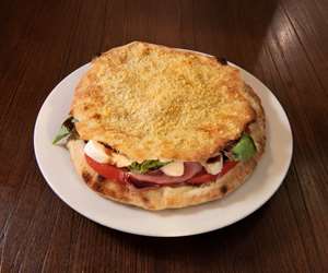 Prosciutto Puccia served with burrata cheese, mozzarella, Parma prosciutto, arugula, tomatoes, basil