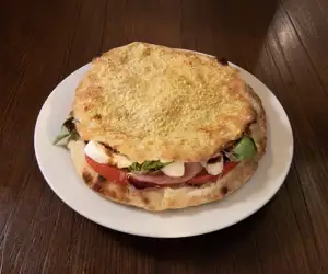 Prosciutto Puccia served with burrata cheese, mozzarella, Parma prosciutto, arugula, tomatoes, basil