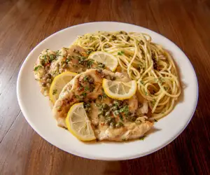 Chicken Picatta, served with a side of spaghetti in a lemon caper sauce